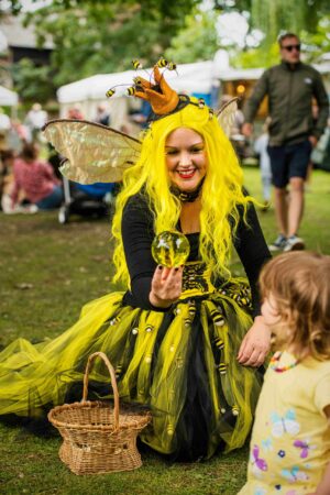 Amy as Bumblina Queen Bee conact juggling for a young child at Sidmouth Festival
